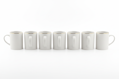 Set of 6 white ceramic mugs with gold rim arranged in a row