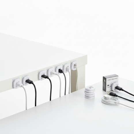 White adhesive cable management clips organizing cables on a desk