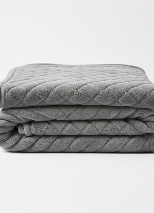 Soft grey weighted comfort blanket neatly folded on white background