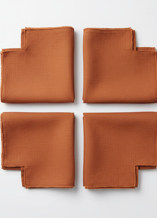 Set of 4 terracotta linen napkins neatly folded on white background
